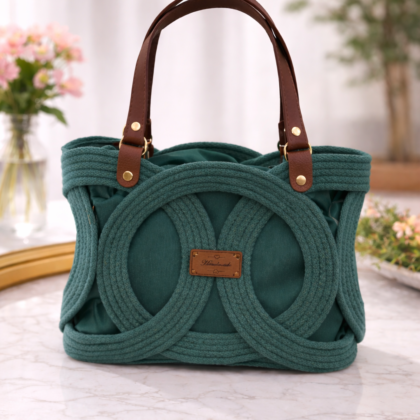 spruce green infinity handbag with brown handles on marble table, handwoven cotton cord structured bag