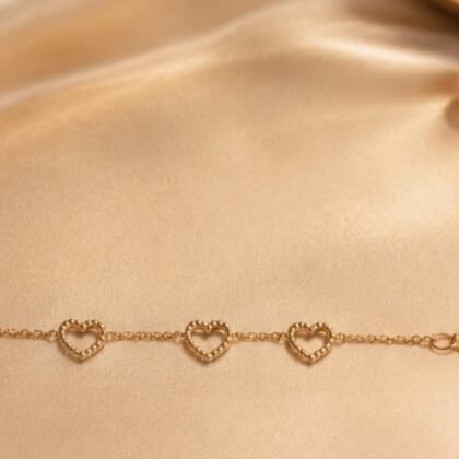 Made in Italy gold heart bracelet with open-heart charm details Delicate Italian gold-plated sterling silver heart bracelet on wrist Fine chain bracelet with tiny heart accents, Made in Italy jewelry Romantic gold heart bracelet styled in lifestyle setting Close-up of dainty Italian heart charm bracelet