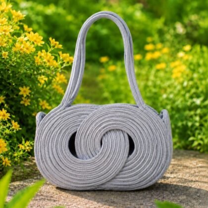 Infinity Collection gray woven handbag with double handles Sculptural gray woven handbag with circular detailing Gray woven shoulder handbag with lined interior Boutique gray handbag styled outdoors