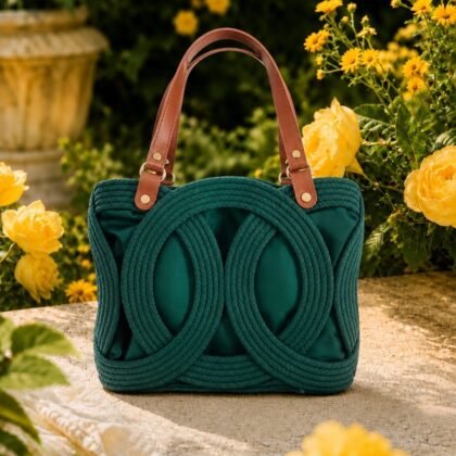 Emerald Green Infinity Handbag with brown leather handles Infinity Collection emerald green structured woven handbag Emerald green handbag with sculptural circular woven detail Side profile of emerald green woven handbag with leather handles Structured emerald green statement handbag with protective feet