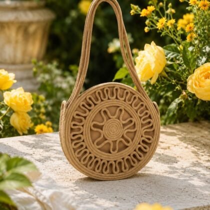 Toast tan Sol Circle Bag from Infinity Collection styled on model Round woven shoulder bag with sunburst texture in neutral tone Sculptural toast tan circle handbag with double straps Infinity Collection round bag in garden lifestyle setting Neutral woven circular handbag with structured silhouette