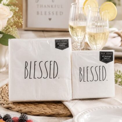 Rae Dunn Blessed luncheon and beverage napkin bundle styled on a neutral brunch table with white plates, glasses, and soft natural lighting.