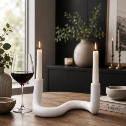 Lily + Faye white ceramic candle holder with sculptural curved design holding two taper candles in a modern home setting.