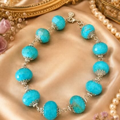 Aqua Muse turquoise-hued faceted statement necklace with ornate silver-tone accents displayed on a jewelry stand