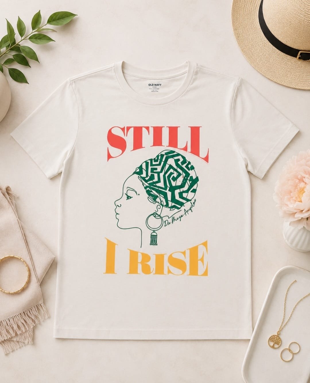 Old Navy “Still I Rise” graphic tee with Afrocentric-inspired illustration and bold multicolor lettering on cream background.