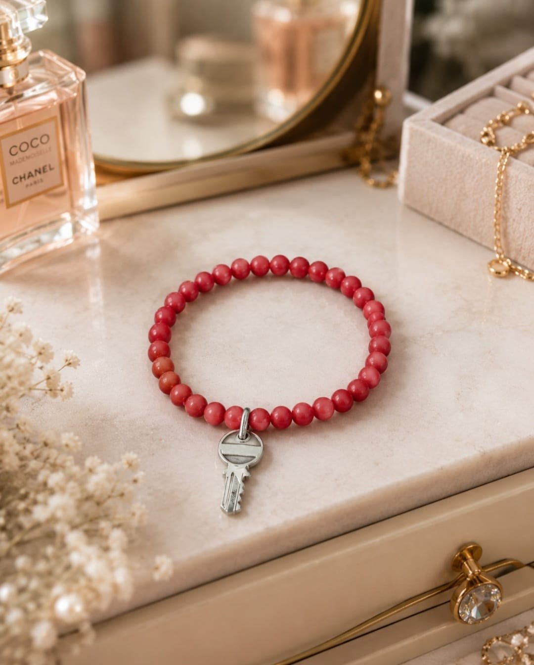 Red beaded unisex stretch bracelet with silver-tone key charm displayed in a clean minimalist jewelry setting.